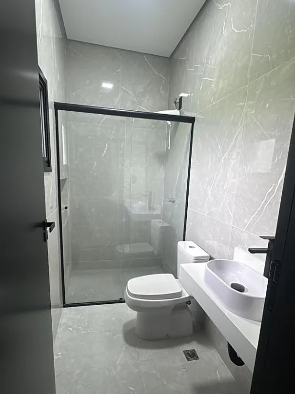 Banheiro com porcelanato marmorizado e box de vidro