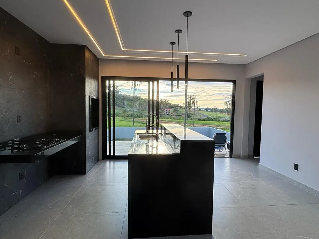 Cozinha com ilha em granito preto e iluminação de LED no forro